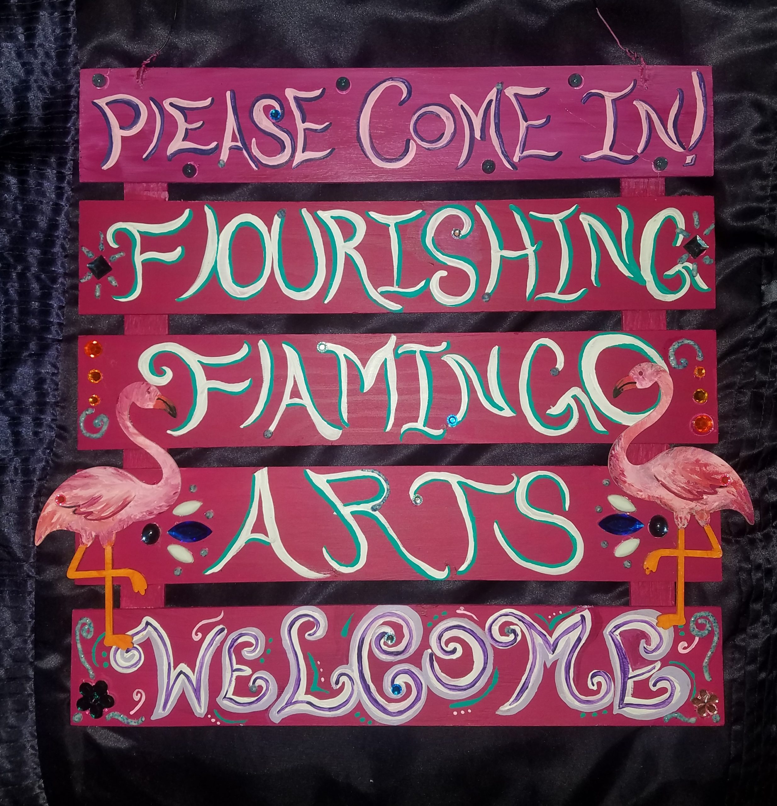Hand-painted pink Flourishing Flamingo Arts welcome sign
